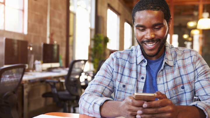 Uomo sorridente che usa il suo telefono