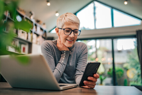 Image of a woman on a computer and looking at her phone