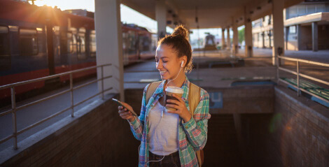 Image of a woman looking at her phone outside with headphones in