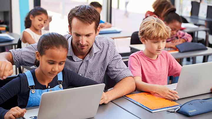 Young man helping a child use something on a laptop