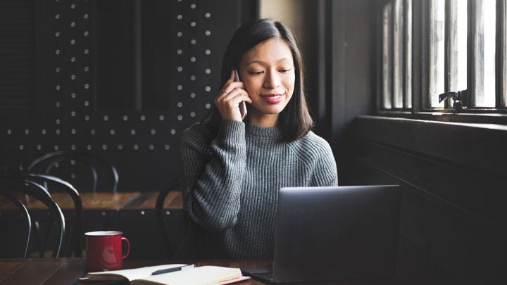 Mujer en el teléfono sentada con su laptop